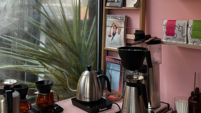 Interior of Paradox Design + Coffee with pink walls, coffee equipment and a magazine stand