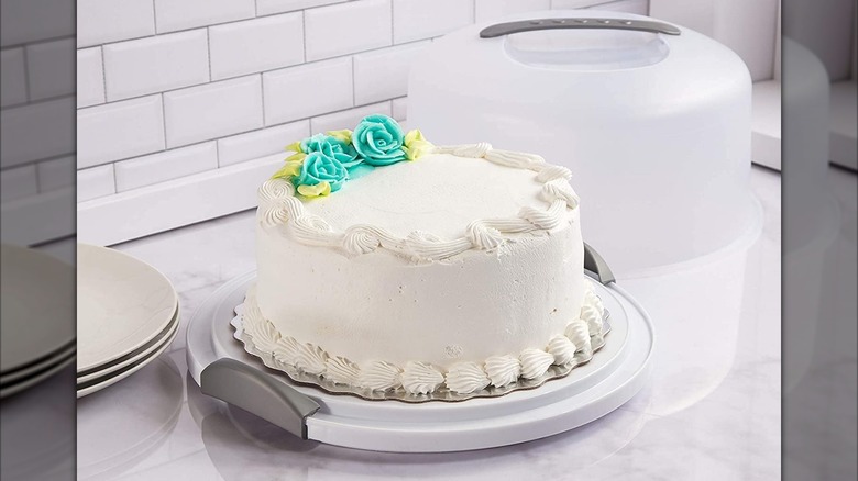 A Sterilite cake carrier on a counter with a white-frosted cake