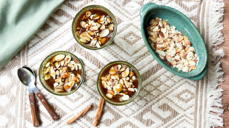 Almond chai chia pudding served in three dessert glasses, next to a bowl of slivered almonds