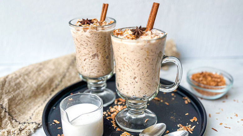 Coconut chai rice pudding served in two glass mugs, each topped with a cinnamon stick and star anise