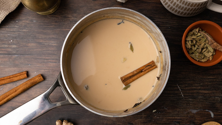 Maple chai latte mixture in a saucepan with a cinnamon stick