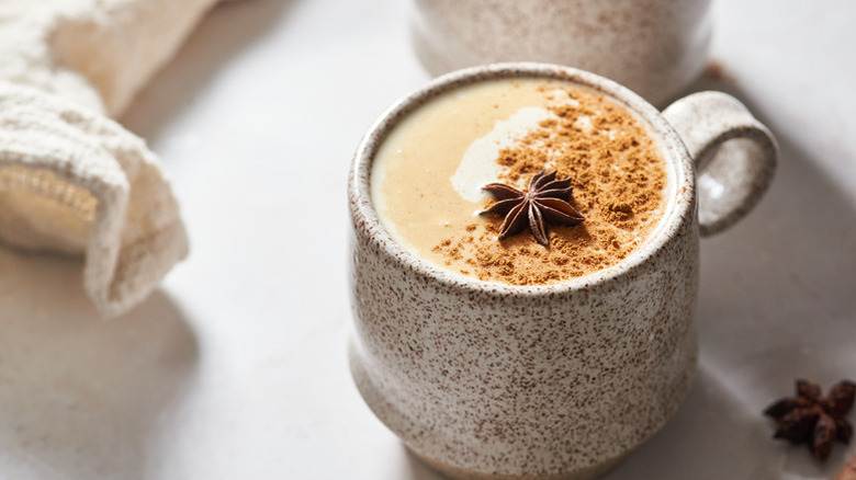 Oat milk chai latte in a mug, garnished with star anise and ground cinnamon