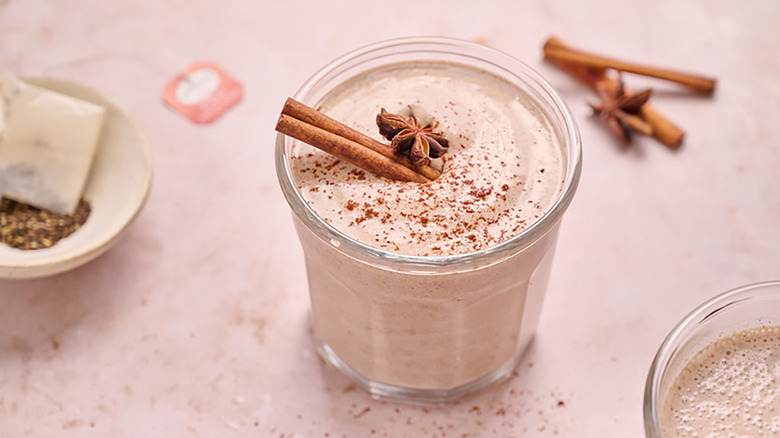 Vanilla chai protein smoothie in a glass, garnished with a cinnamon stick and star anise