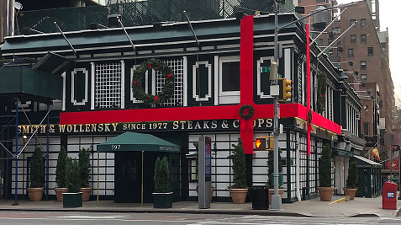 a Smith & Wollensky location in New York with an oversized red ribbon on the outside of the black and white building.
