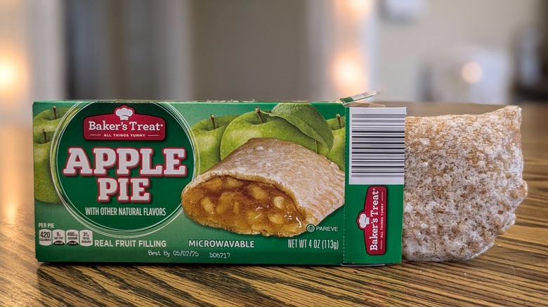 A packet of apple pie on a wooden table with the apple pie partially out of the box