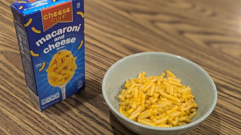 Bowl of macaroni and cheese next to box on wooden table