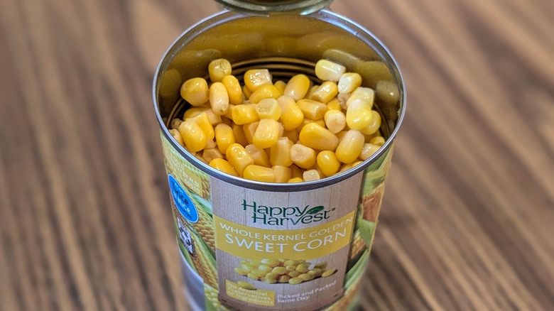 Top view of open can of corn on wood background