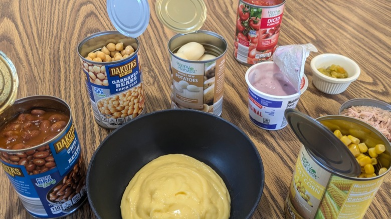 Open containers of various Aldi foods and bowl of pudding on wood table