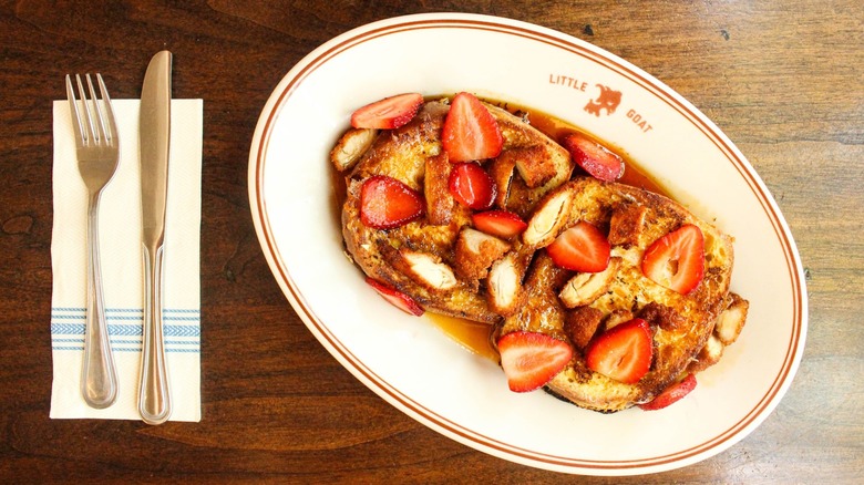 Plate with strawberry-covered French toast and knife and fork