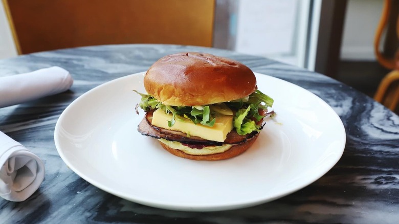 Breakfast sandwich on white plate with cloth napkins and marble table
