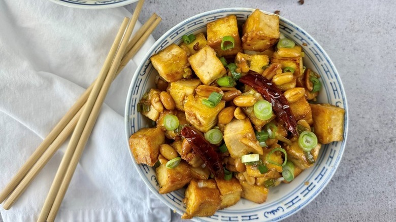 Kung pao tofu in bowl with dried chiles, peanuts, and scallions
