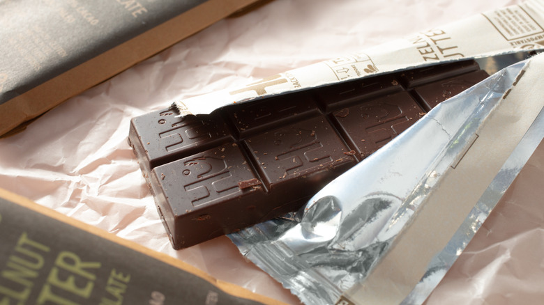 Open bar of Hu Kitchen chocolate on paper alongside two sleeves