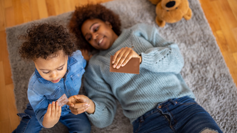 Mother and son on a carpet sharing a chocolate bar