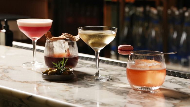 Four cocktails resting on a restaurant bar.