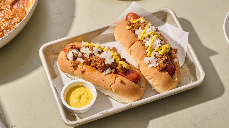 Two Coney Island hot dogs on a tray with dipping sauce