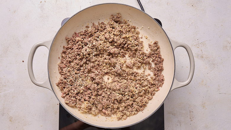 Aerial view of cracker crumbs stirred into beef in a pot