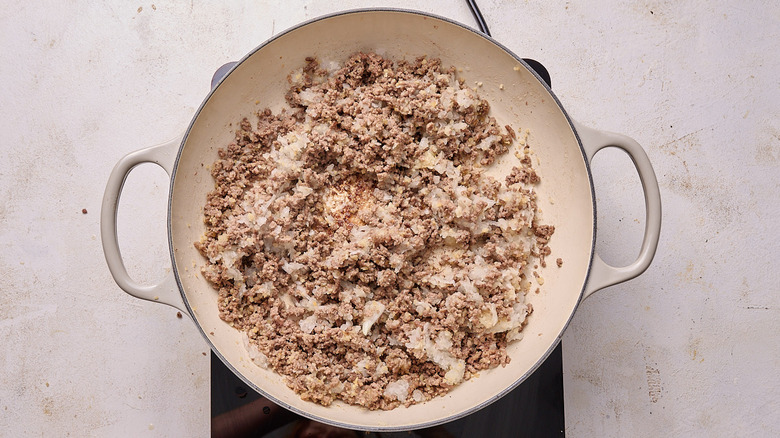 Aerial view of onions stirred into beef mixture in pot