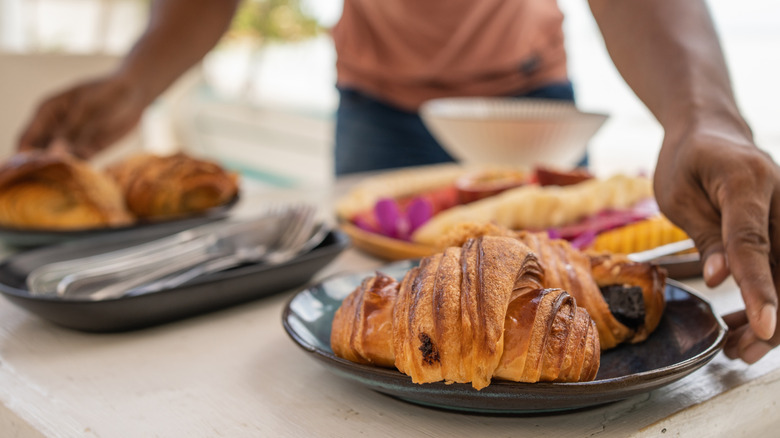 someone sitting out breakfast foods including croissants
