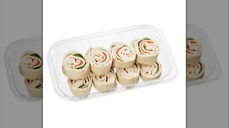 A Kirkland Signature Roasted Chicken & Swiss Roller Tray with two rows of sandwich pinwheels inside on display