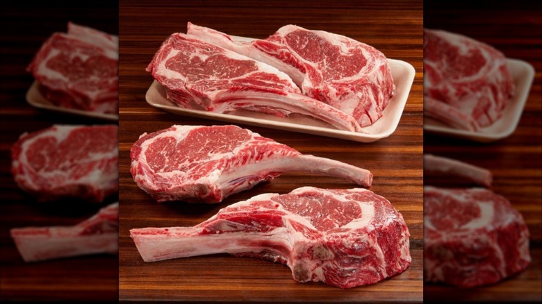 Four raw Kirkland Signature Prime Bone-In Ribeye steaks on wooden surface