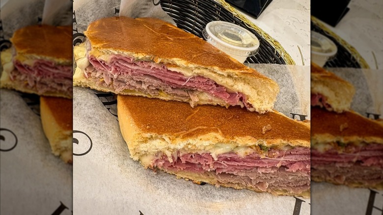 Cuban sandwich from Sanguich Miami sliced and served with a dip inside a basket