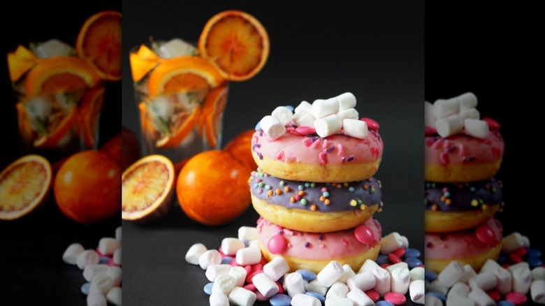 Stack of donuts in front of orange garnished cocktail