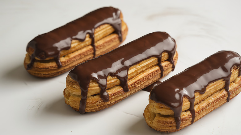 three eclairs with chocolate dripping down sides