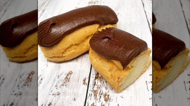 chocolate eclairs on display with one cut in half so you can see the cream filling