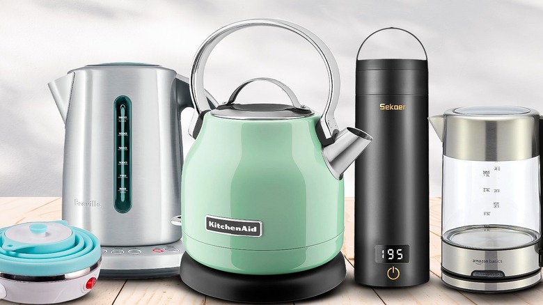 Five electric tea kettles lined up on a wooden tabletop against a white-and-gray background
