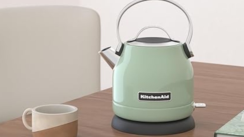 Pistachio KitchenAid electric kettle next to a mug on a desktop