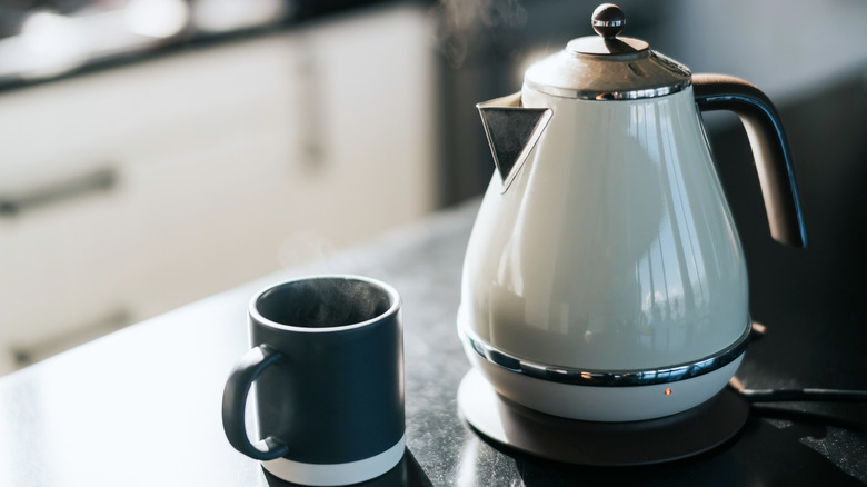 An electric kettle and mug on a black kitchen counter