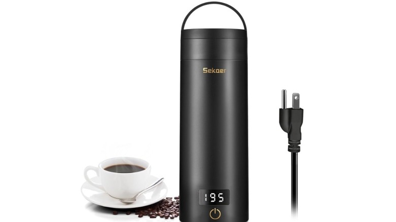 Sekear travel electric tea kettle next to a cup of coffee against a white background