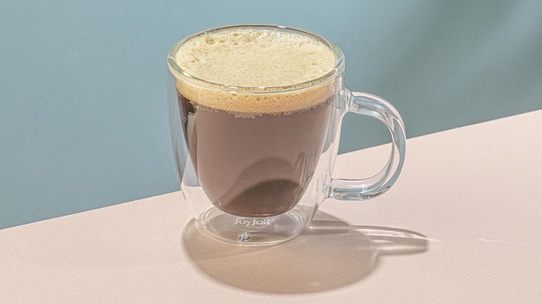 Close-up of a JoyJolt Savor espresso mug full of a frothy espresso on a table