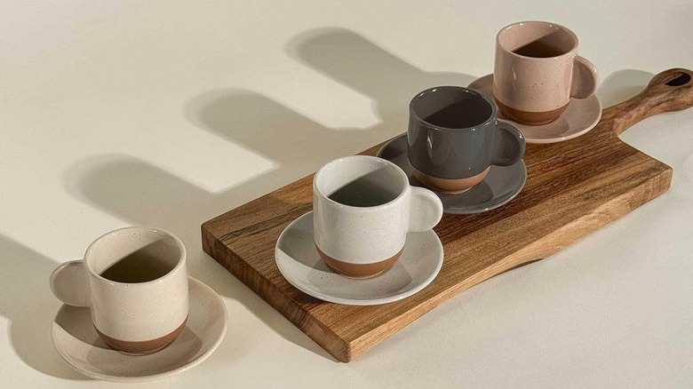 Four different-colored Mora espresso cups on a board, with a plain white background