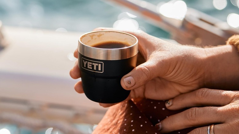 Full YETI espresso cup grasped in a hand outdoors