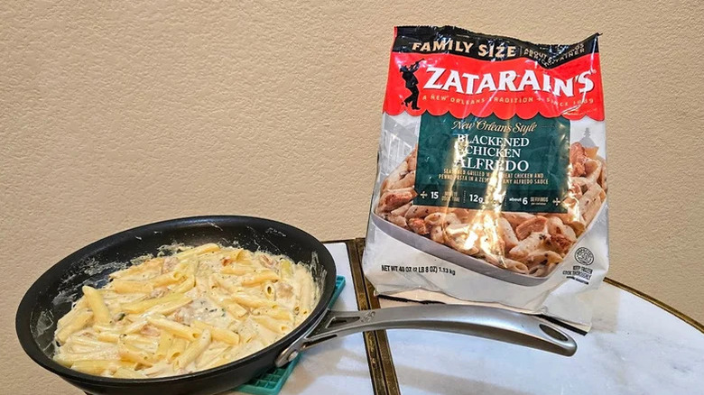 Bag of Zatarains Alfredo frozen meal with a skillet of the pasta