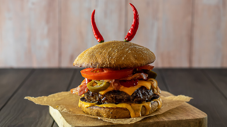 Spicy burger with peppers on wooden board