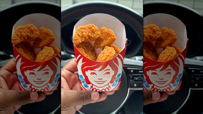 Hand holding carton of Wendy's Spicy Nuggets