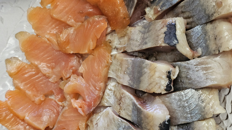 Raw filets of salmon and herring on a white plate