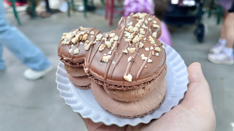 Hand holding the Mickey-Shaped Macaron in a white dish