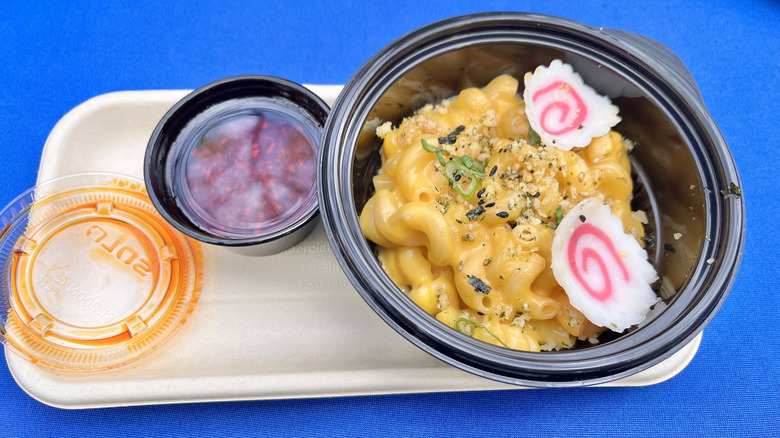Ramen Mac & Cheese with fish cakes on a tray against a blue background
