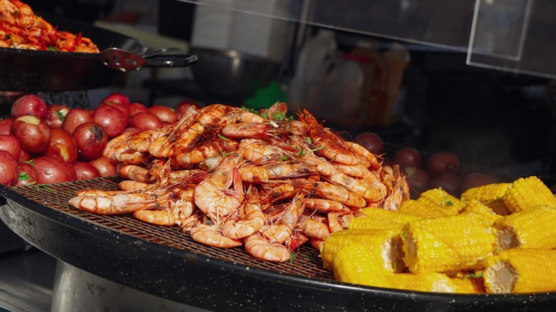 Shrimp, corn cobs, and onions on a grill