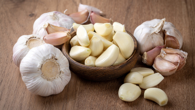 Heads and cloves of garlic in a wooden bowl and on a wooden surface