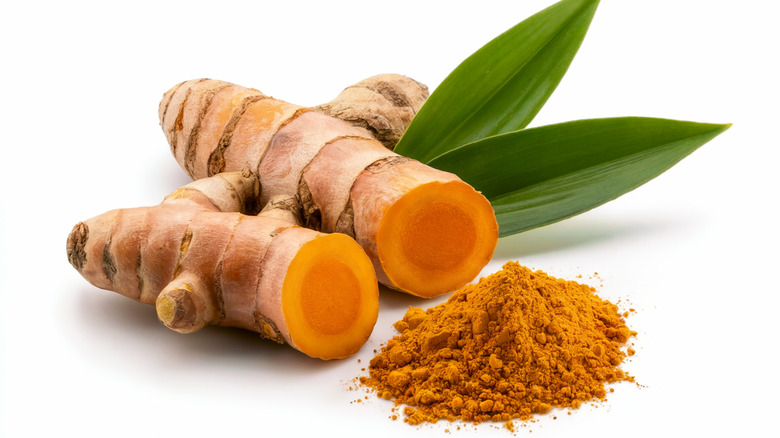 Turmeric root and powder on a white surface