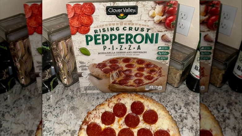 Box of Clover Valley rising crust pepperoni pizza leaning on a kitchen counter beside pizza