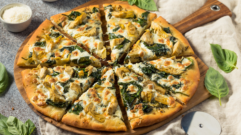 Spinach and Artichoke pizza on wood board