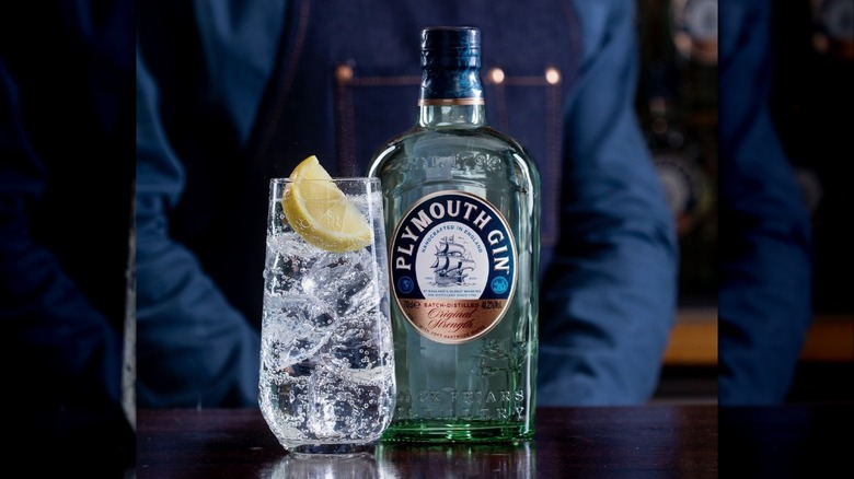 Bottle of Plymouth Gin next to a G&T with a lemon wedge