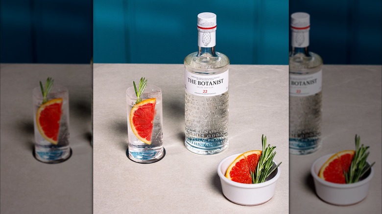 Bottle of The Botanist next to a gin and tonic with garnishes