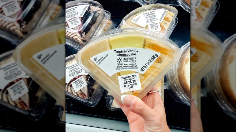 a hand holding a set of Tropical Variety Cheesecake Slices over a freezer case