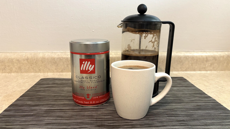 Illy Clasico Illy blend in can, cup, and french press on black placemat